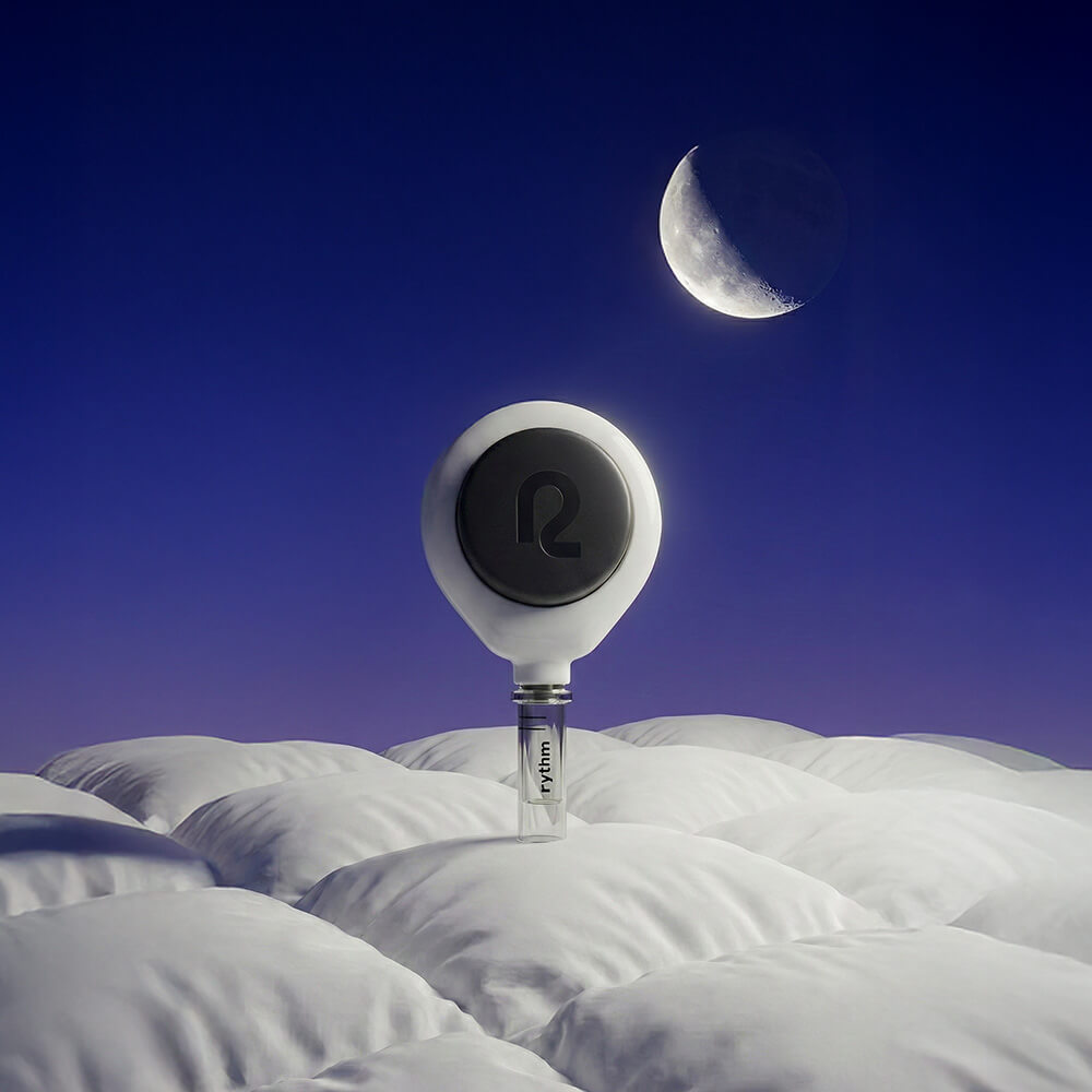 Rythm at-home blood collection device standing upright in soft white bedding under a night sky with a crescent moon, representing sleep and overnight recovery.