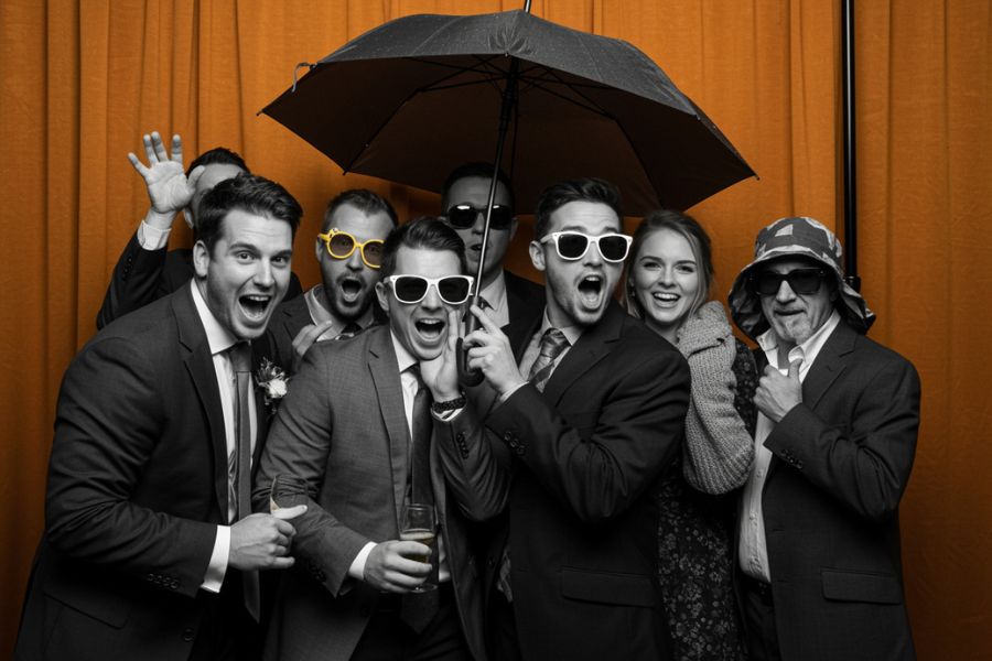 Group of sevent people in a photo booth wearing funny hats.