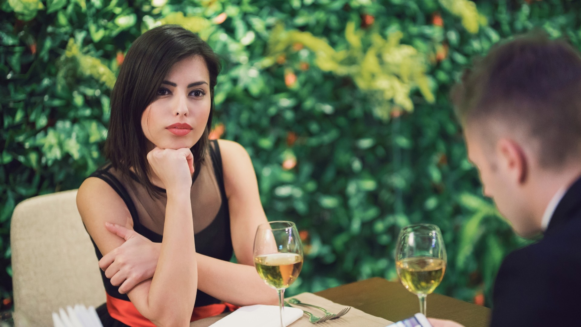 eine frau sitzt mit einem mann in einem restaurant, sie sitzen draußen und trinken sekt