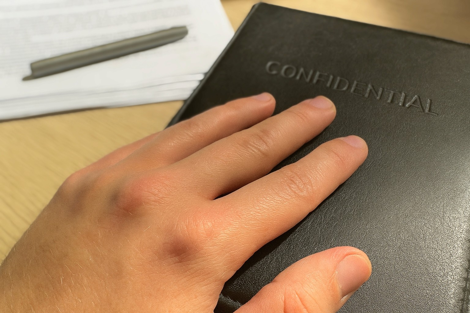 Рука на чорній папці з написом CONFIDENTIAL — конфіденційні документи, професійний переклад і нотаріальне завірення в Одесі