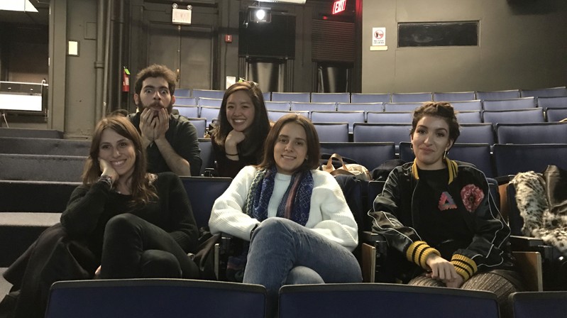 A photo of a group of people sitting in a theater room.