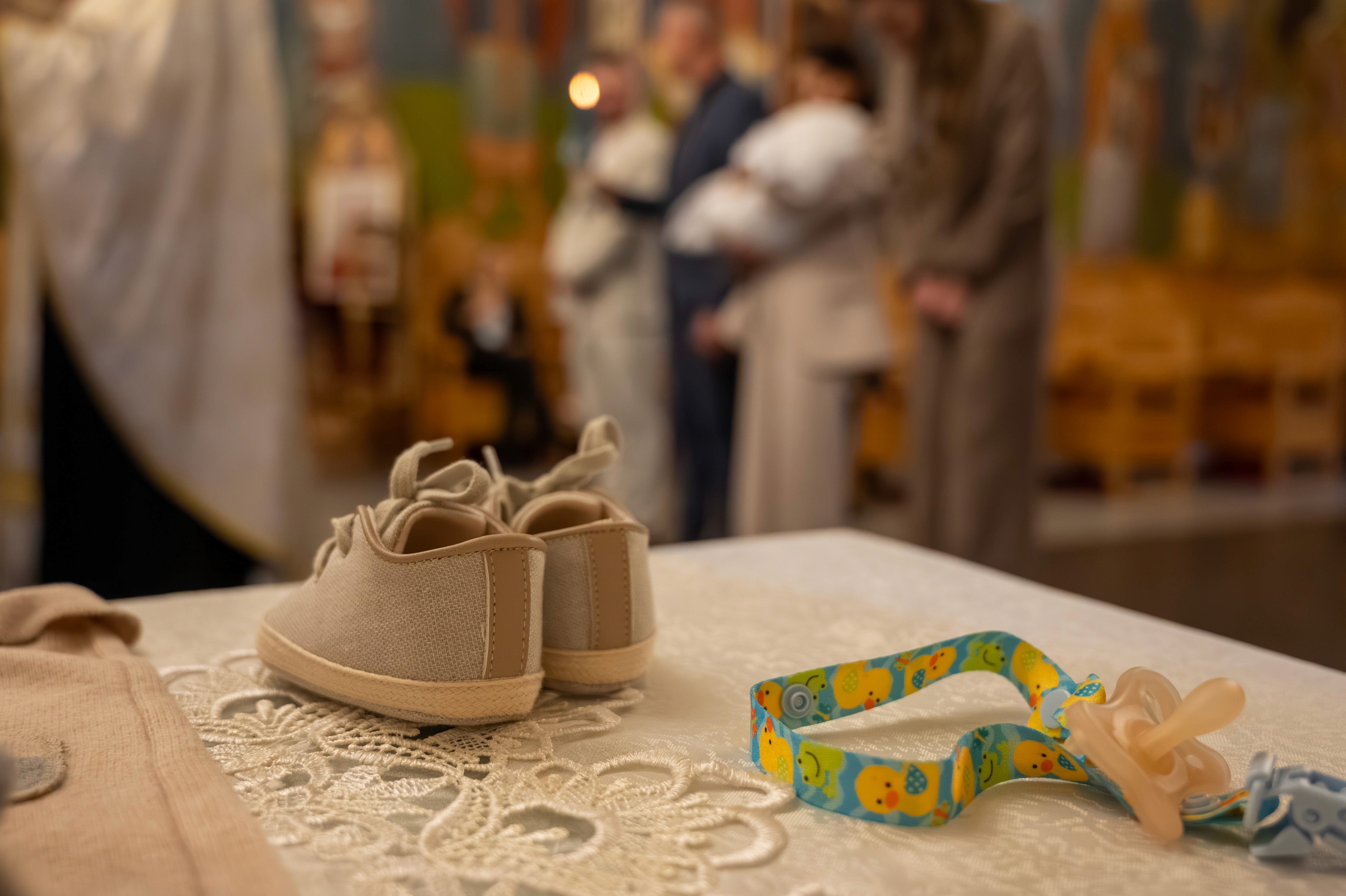 Momentul mirungerii la botez, cu preotul ungând fruntea bebelușului — fotografie emoționantă realizată la un botez ortodox în București.