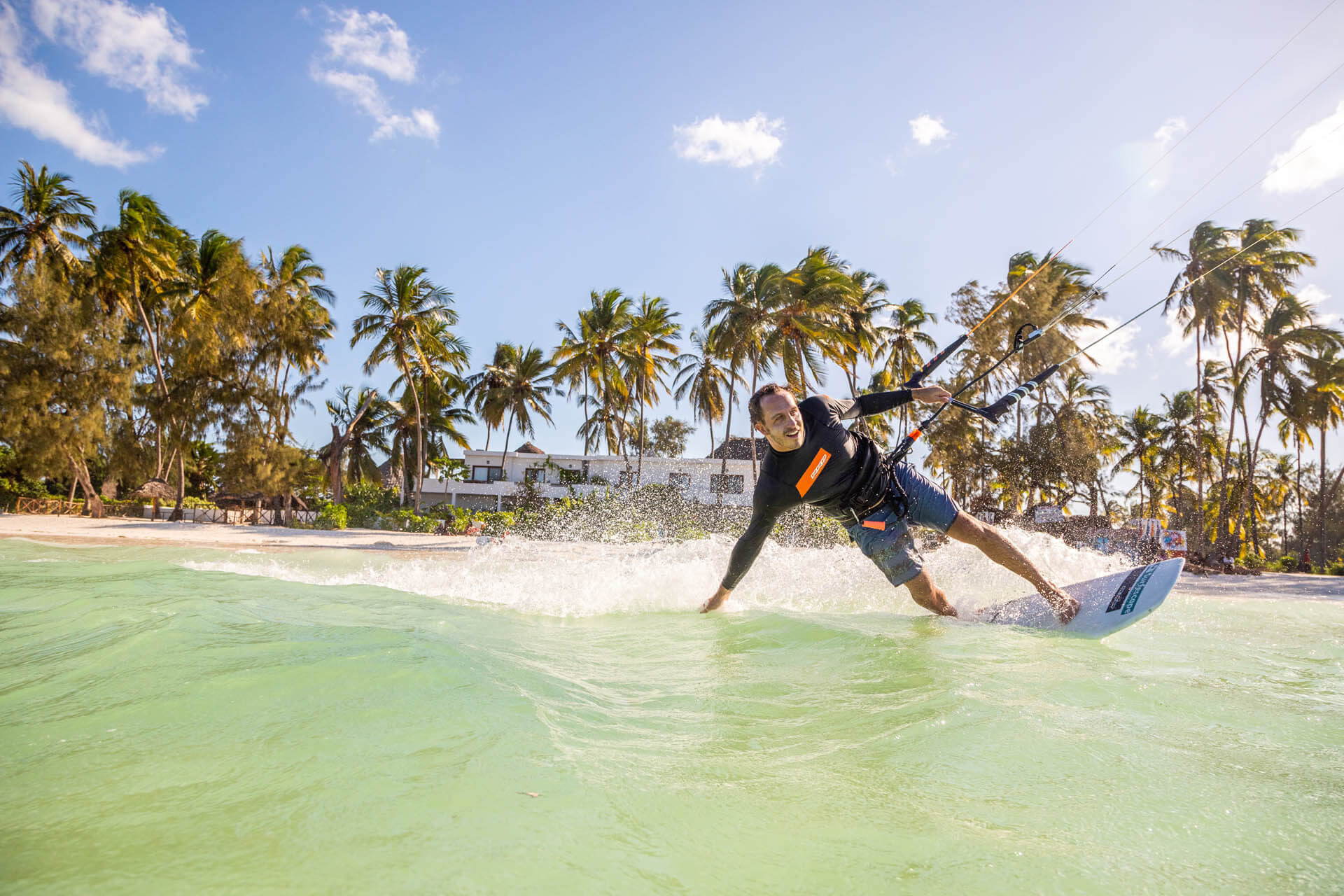 Man kitesurfing on a clear turquoise wave.