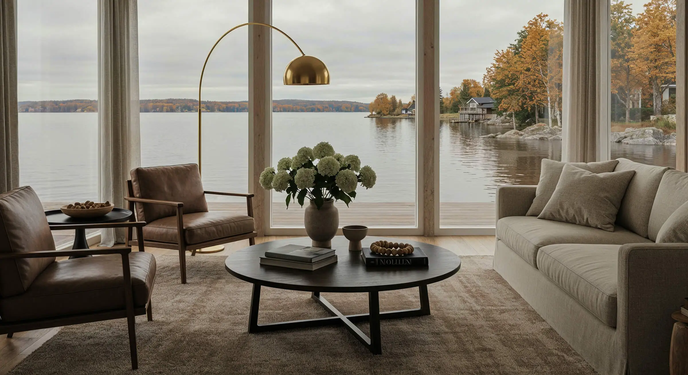 Living room with floor-to-ceiling windows and view of the lake and autumn-colored trees.