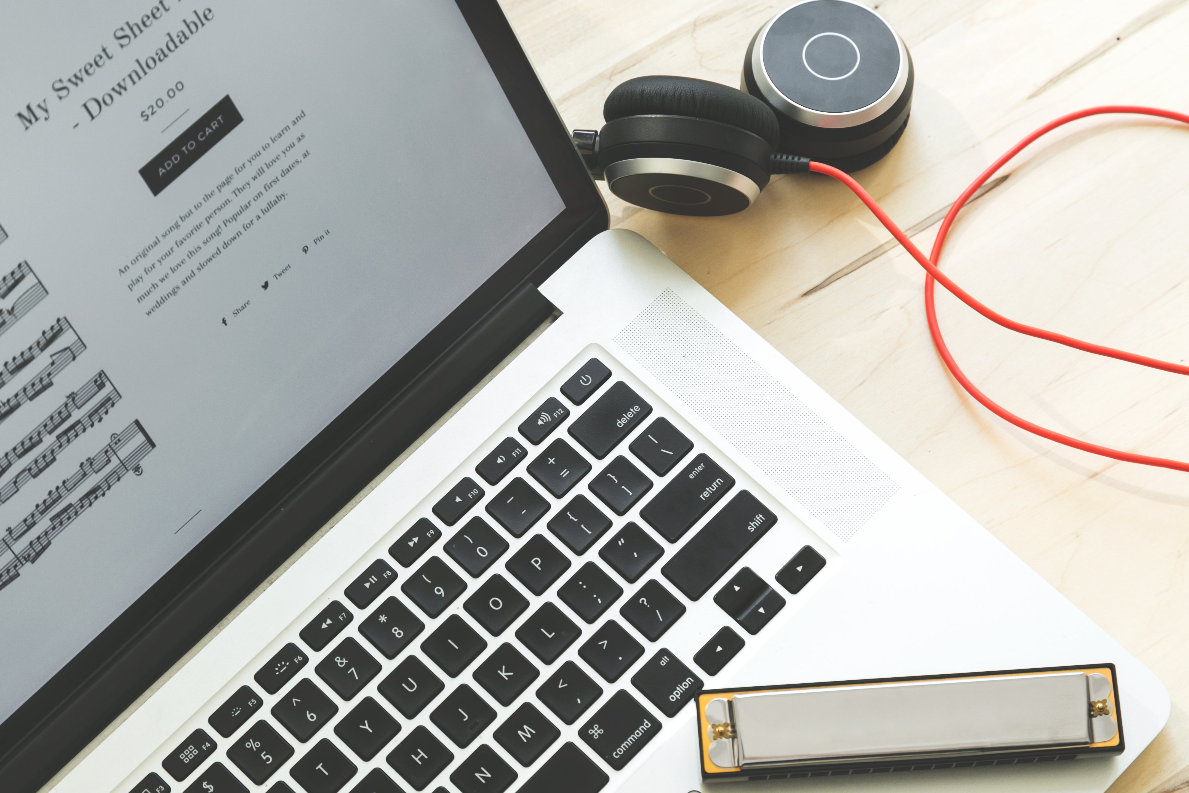 Widok z góry na laptopa, harmonijkę i słuchawki leżące na stole. Na ekranie laptopa znajduje się strona do pobierania nut. - Ilustracja do artkuły o Jak wybrać procesy do automatyzacji w agencji rekrutacyjnej