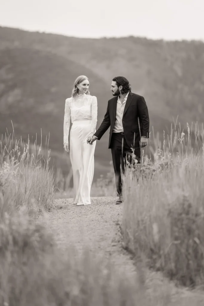 Bride and groom walking together on a mountain trail during their Vail Colorado wedding, black and white portrait captured by Summit Photo and Film wedding photographers.