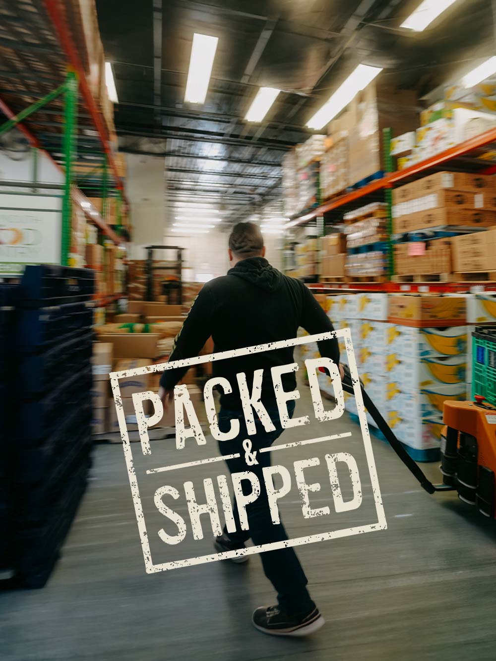 Motion-blurred photo of a person pulling a pallet jack through a warehouse aisle lined with stacked boxes and pallets, with a “PACKED & SHIPPED” stamp graphic overlaid.