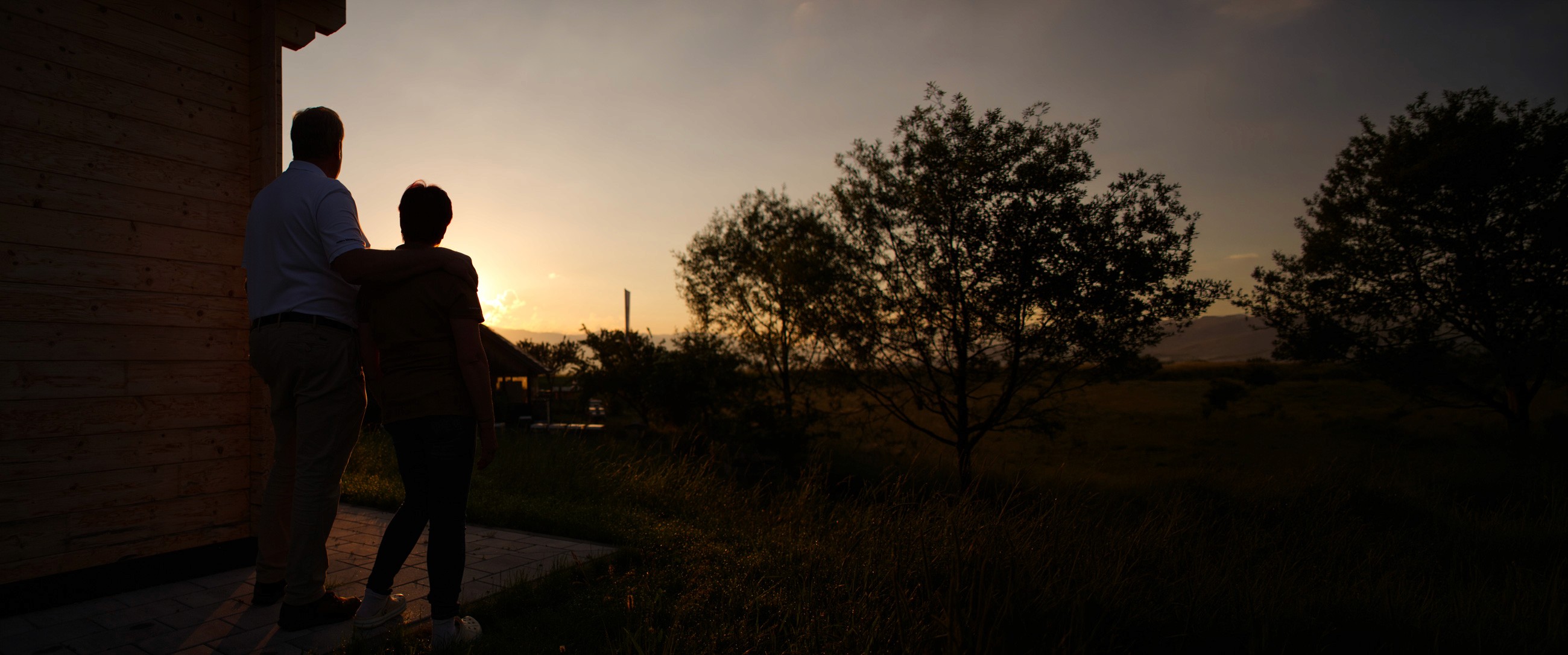 Monika und Bernhard Moser blicken über die Bergwiesen bei Sonnenuntergang