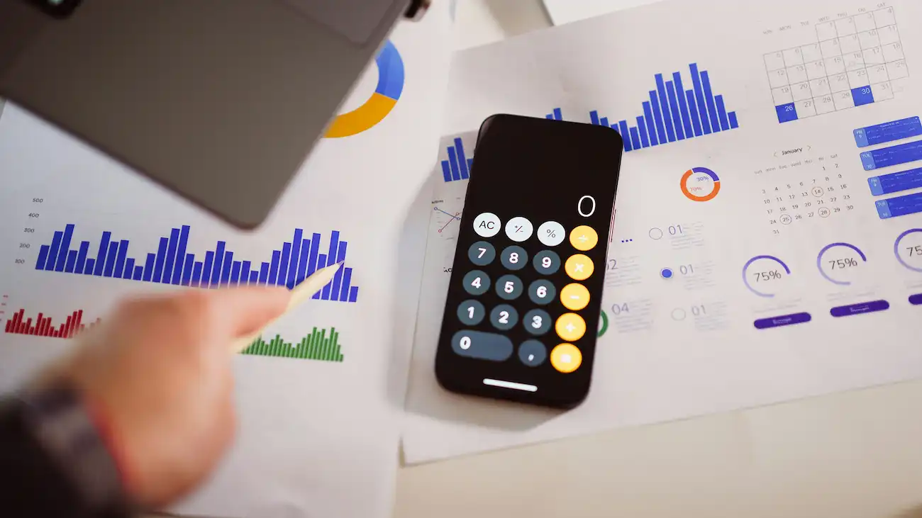 Smartphone calculator on printed analytics charts and graphs — illustrating value-based sponsorship pricing for sports clubs, including reach, activations and reporting.