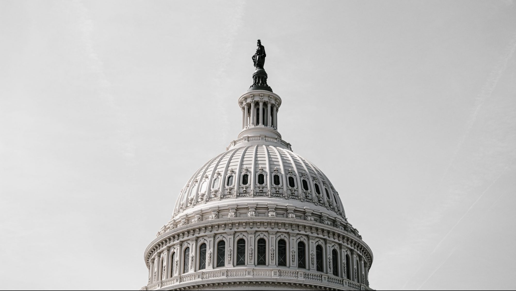 Close-up of the dome of a historic building against a gray sky, emphasizing its architectural details.