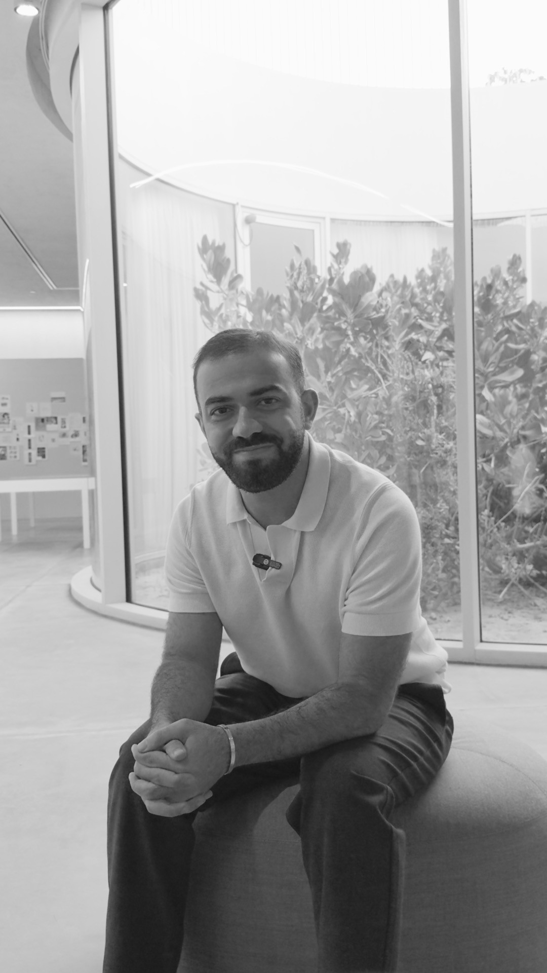 An ostrich is peeking at a man who is reading a newspaper.
