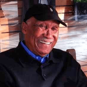 Portrait of Bruce McLeod Jr., a smiling white-haired man in a cap