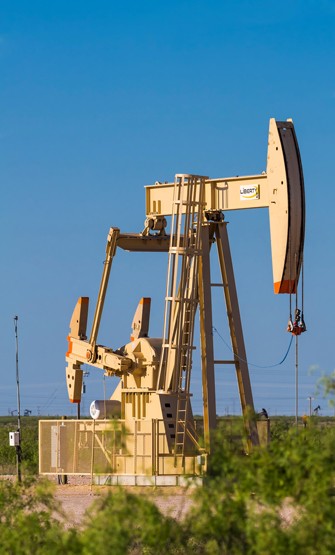 Smiling young man with short hair poses against a dark background, wearing a green button-up shirt.
