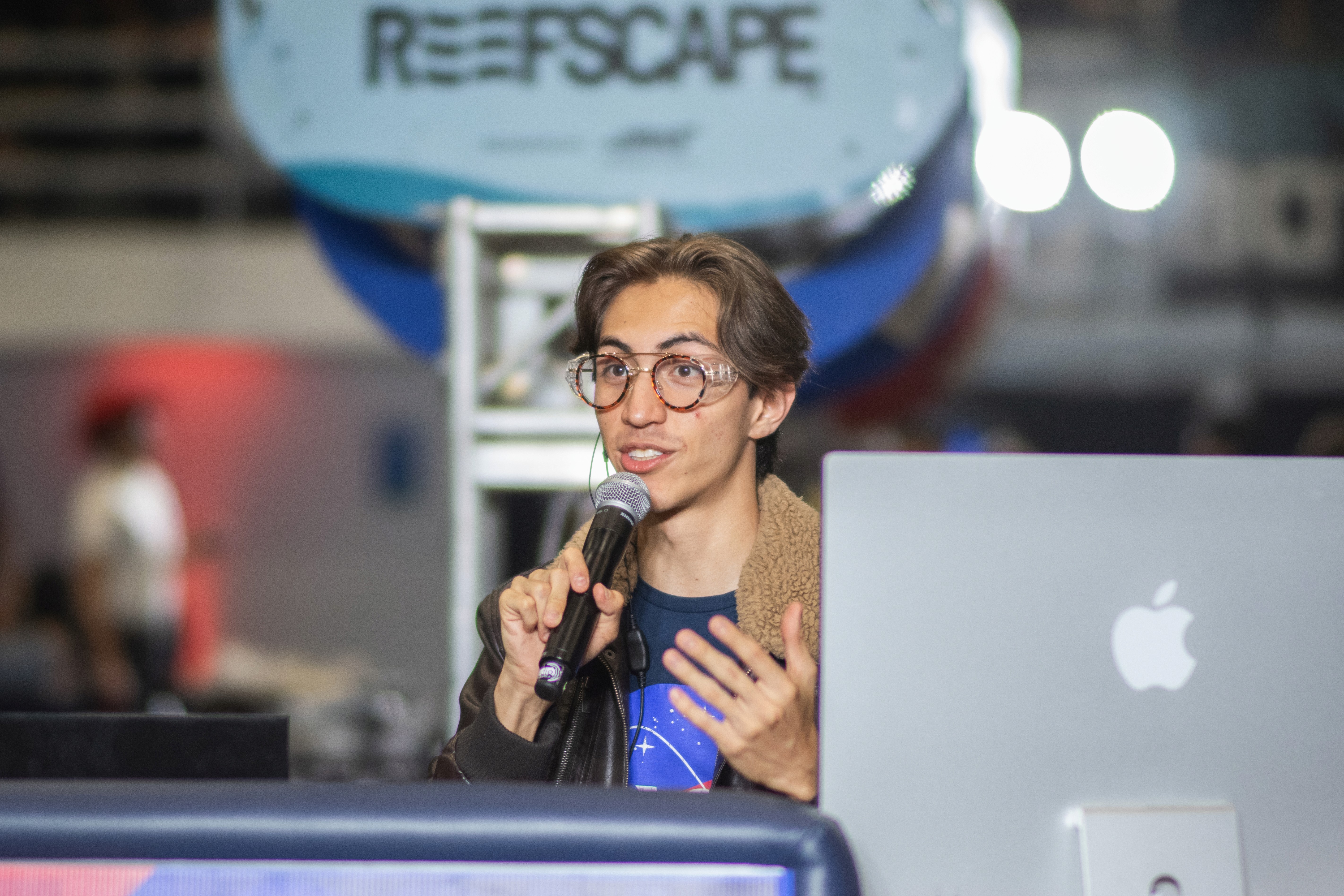 Charles speaks into a microphone and camera.