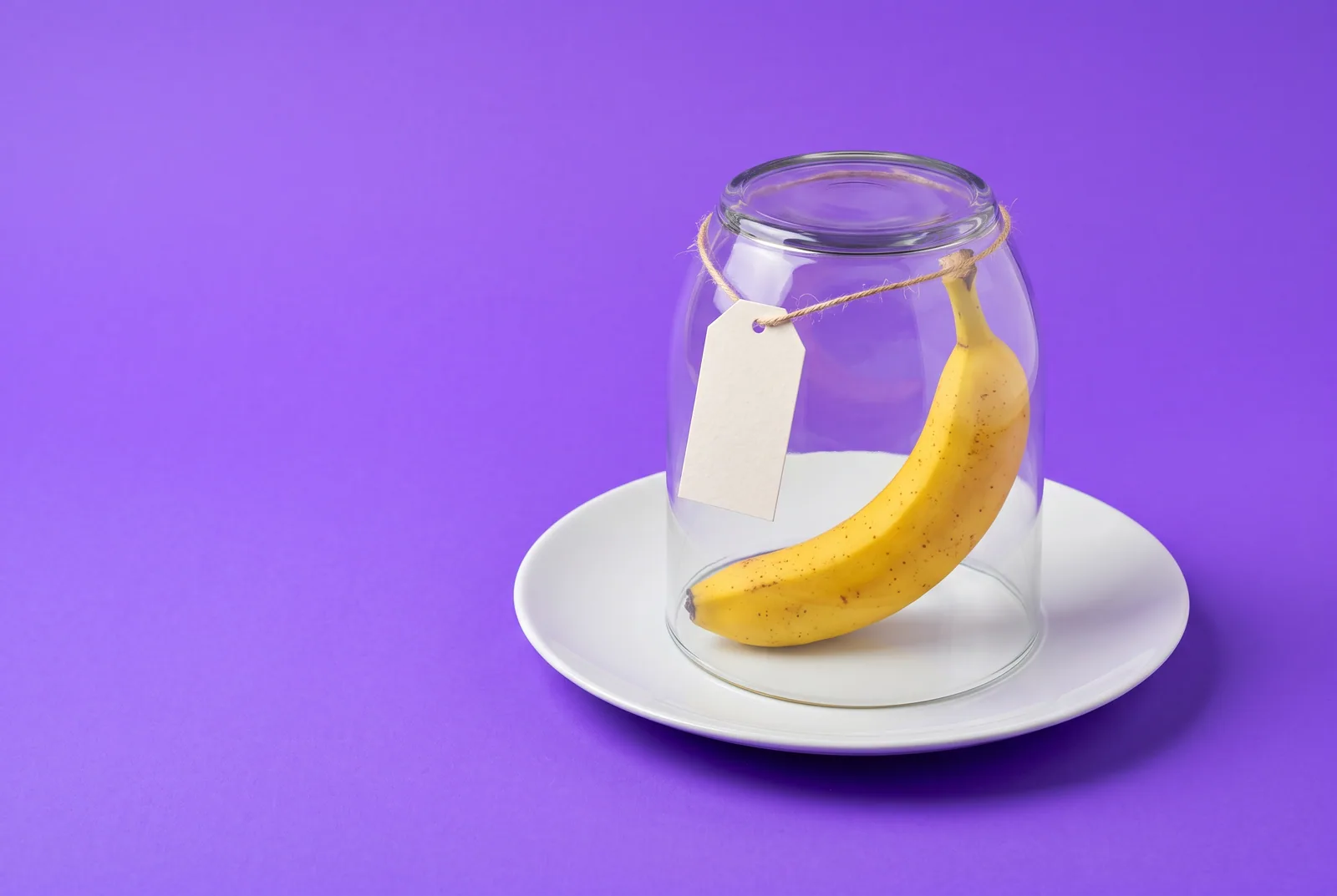 A banana under an upturned glass jar with a blank paper price tag, a playful image for the best free porn blocker