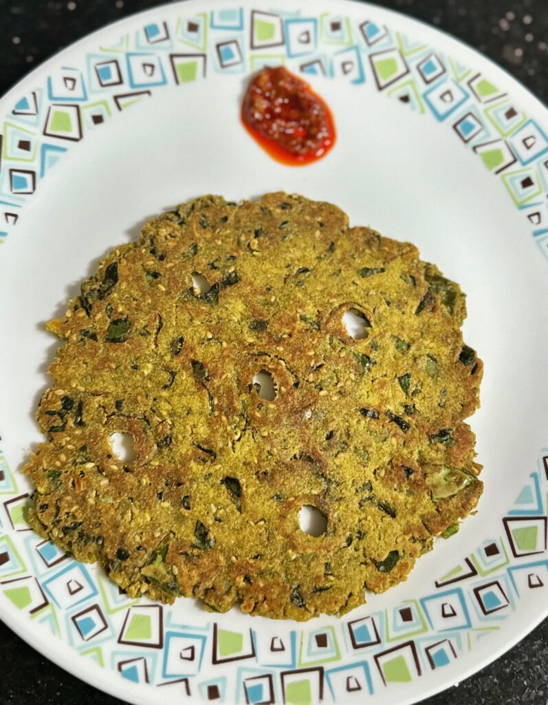 Ratali Bajri Thalipeeth is served with a side of pickle.