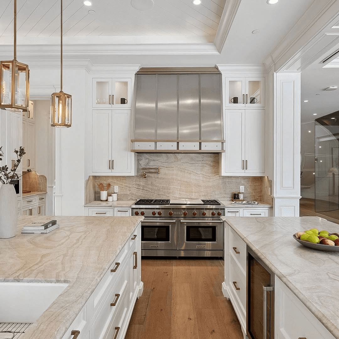 Modern kitchen with white cabinetry, a large island, pendant lights, and stainless steel appliances.