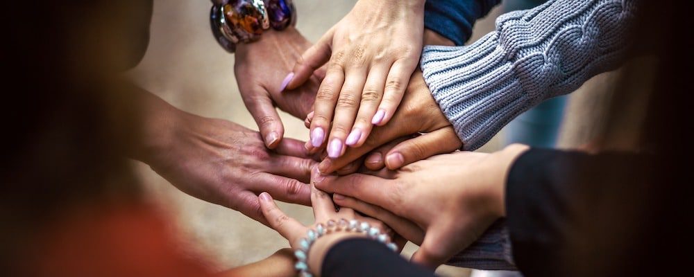 Diverse hands stacked in unity and teamwork.