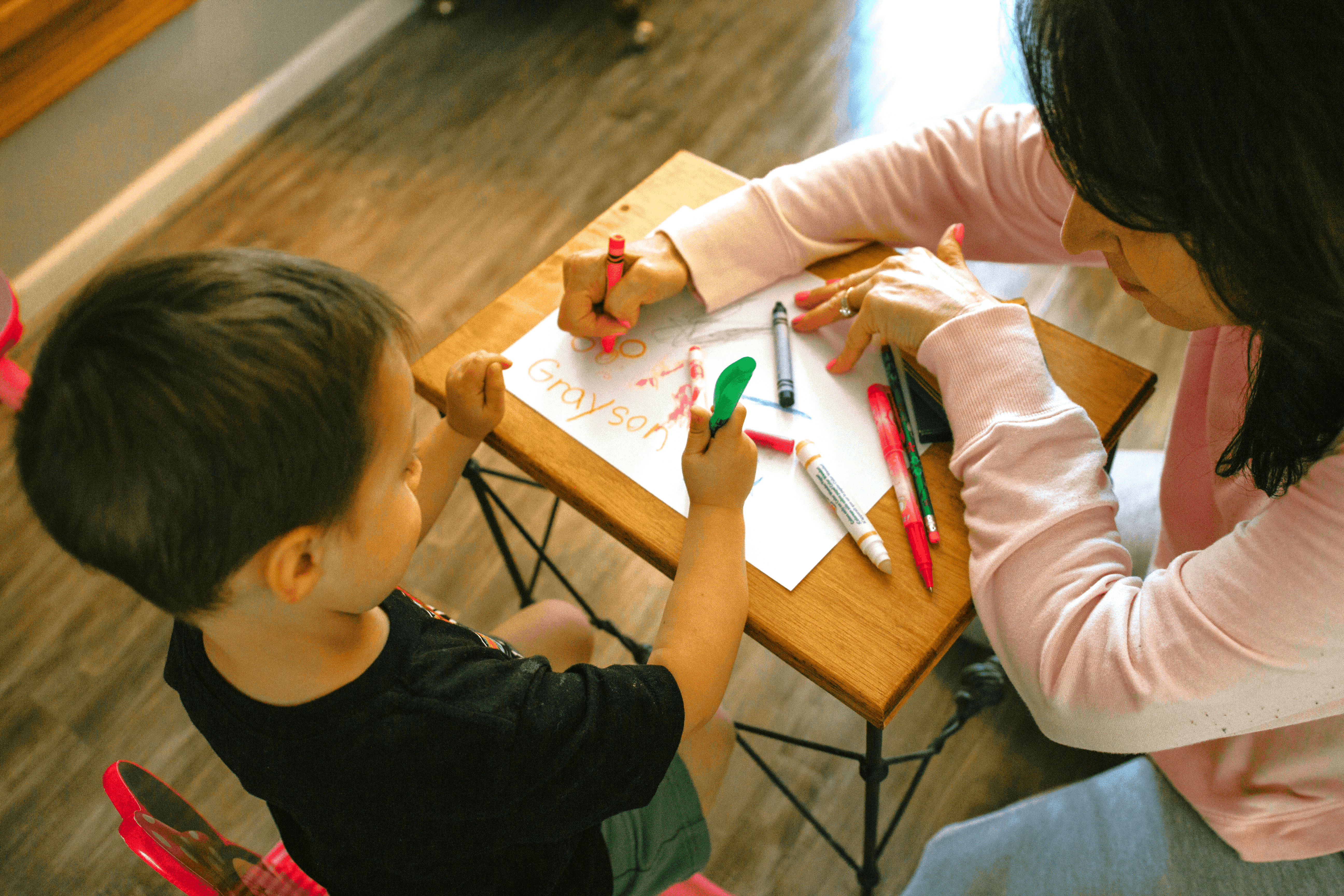 boy in white long sleeve shirt writing on white paper