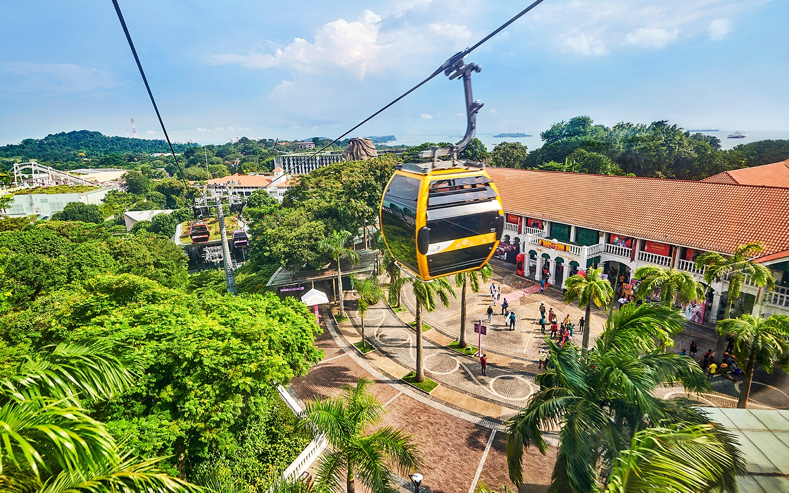 Téléphériques survolant l'île de Sentosa avec la silhouette de Singapour en arrière-plan.