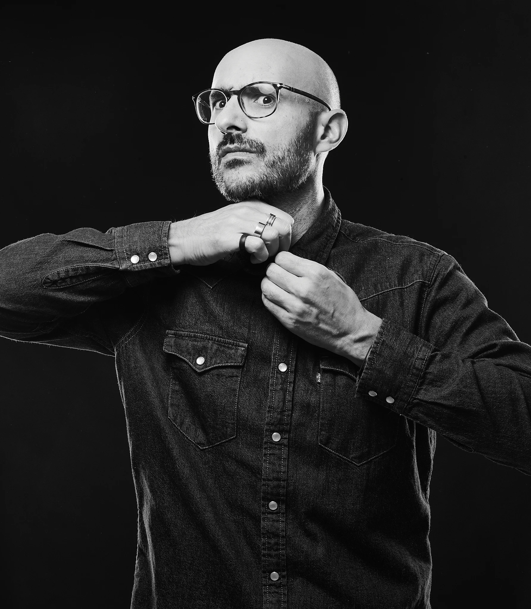 Portrait éditorial en noir et blanc d'un homme à lunettes en costume ajustant son col — Expertise portraitiste et direction d'acteur à La Réunion par David Dijoux