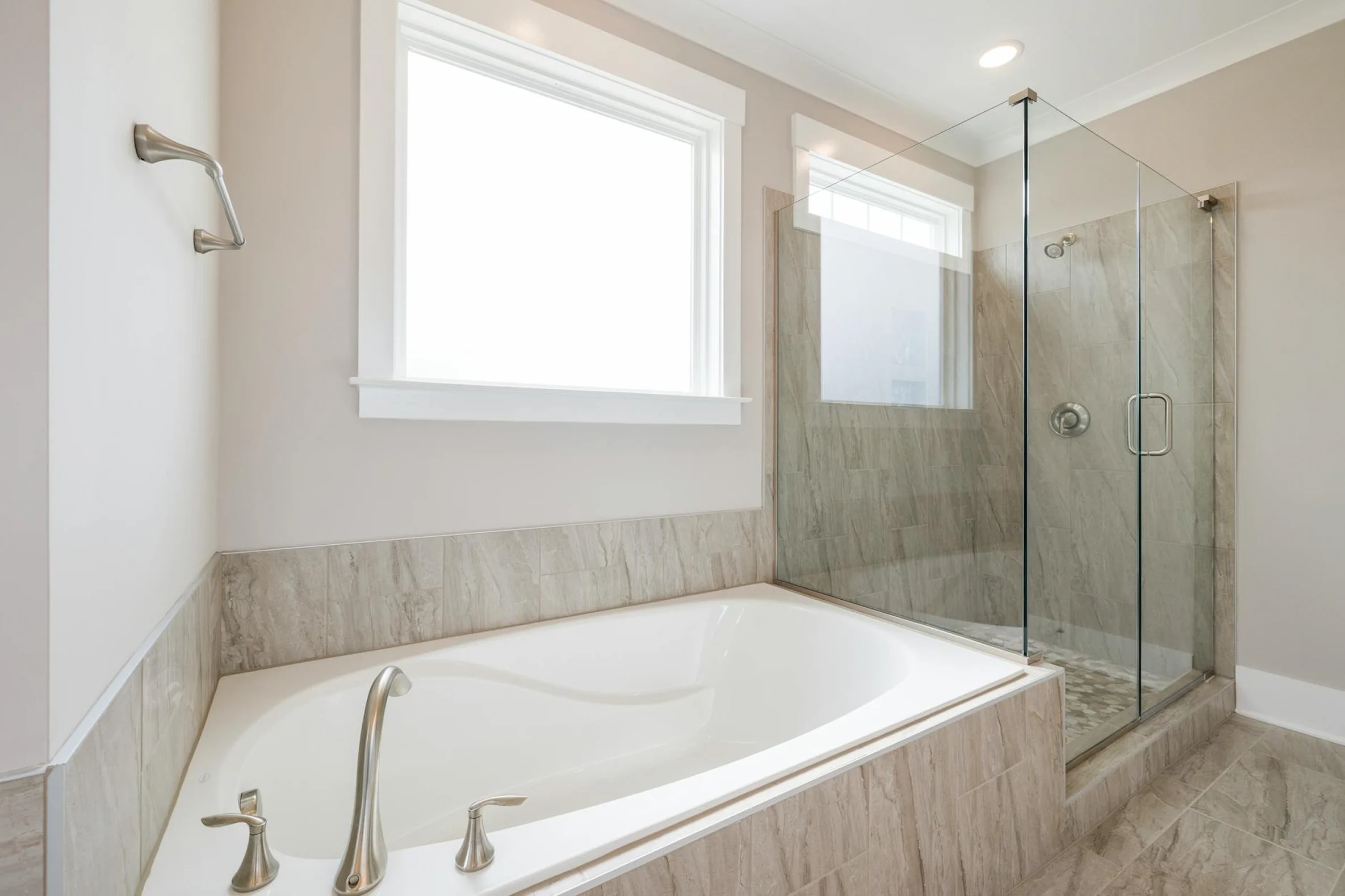 Bright bathroom in the deluxe pool view room with a bathtub, large window, and glass shower area.