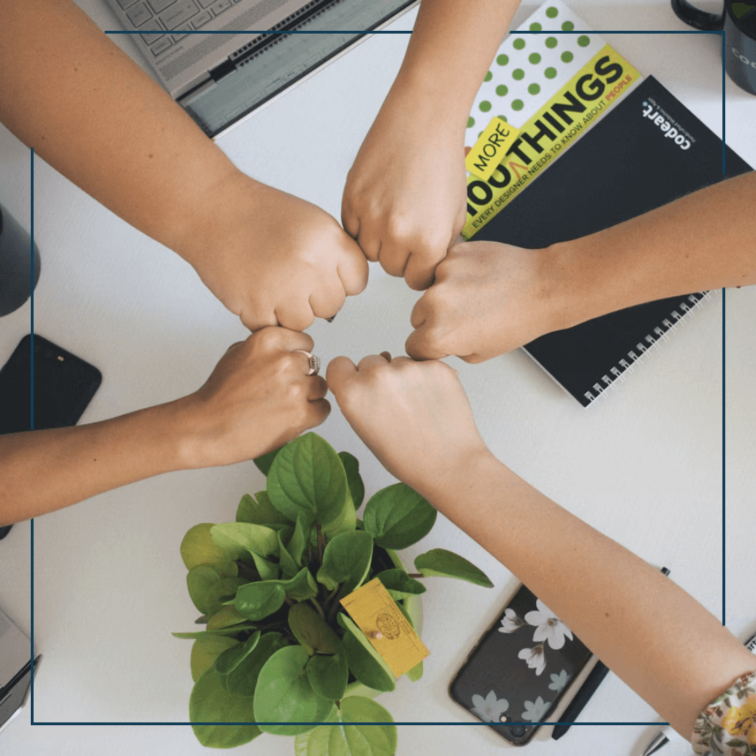 Fünf aufgestreckte Hände die sich in der Mitte zu eimen Riesenfistbump treffen