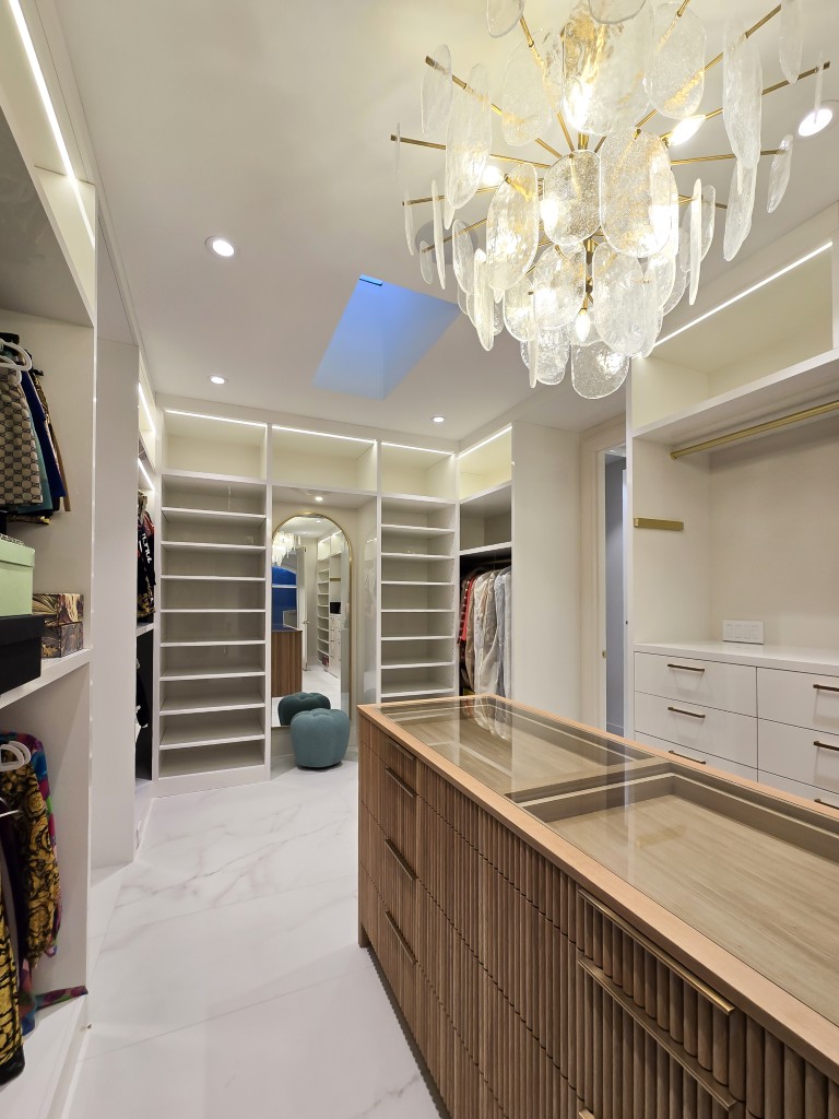Image of Luxurious primary ensuites dressing area with glass chandelier, marble floor, and custom KHD Homes design-build furniture.
