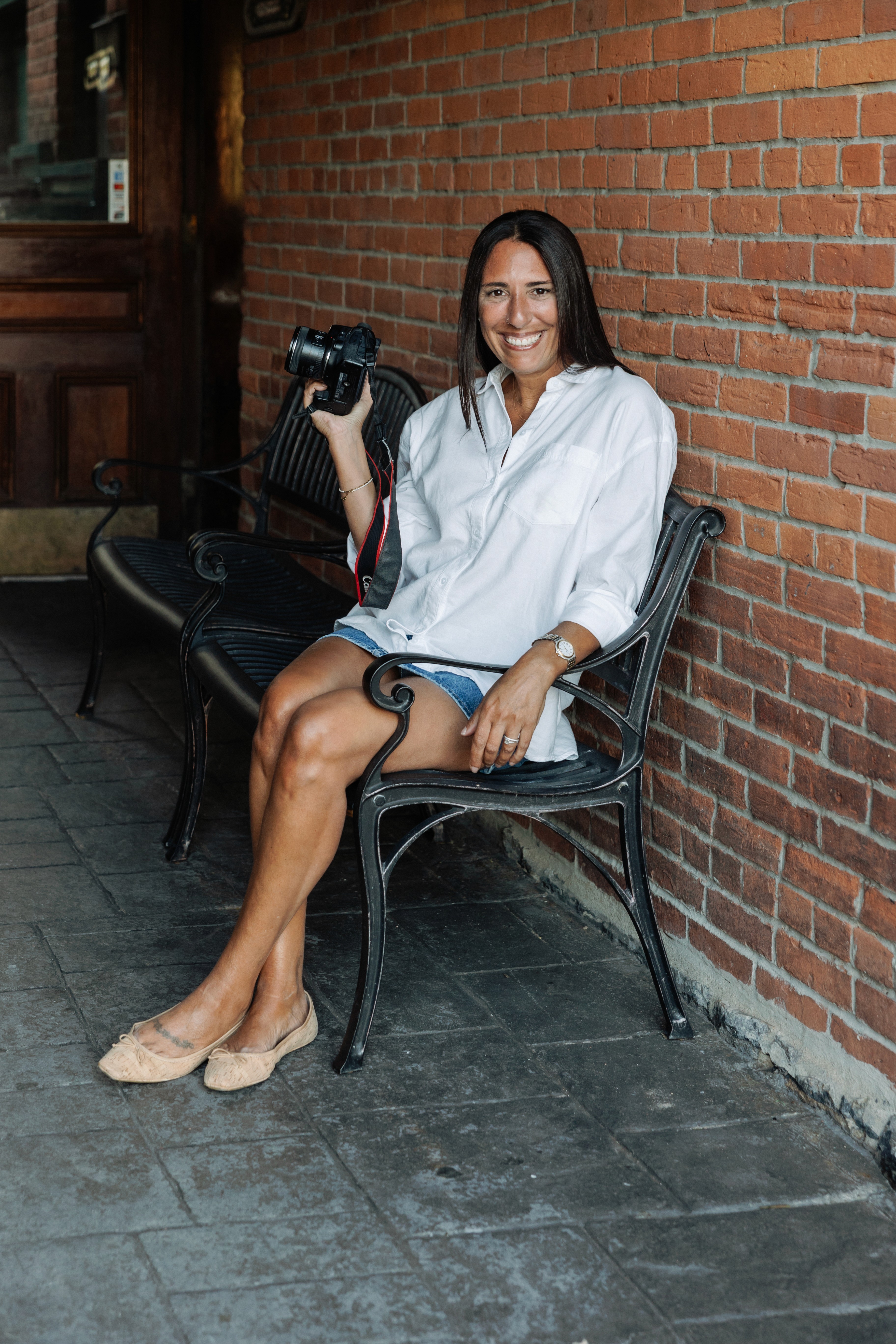 Lizz Spano, New York City and Saratoga Springs photographer, smiling candidly with camera in hand — natural light portrait of the woman behind Lizz Spano Photography.