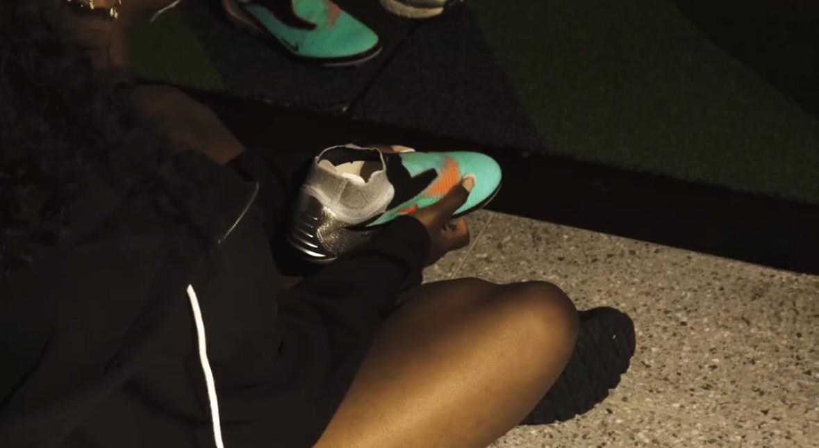 Athlete adjusting a turquoise and orange Nike sneaker during a lifestyle shoot.