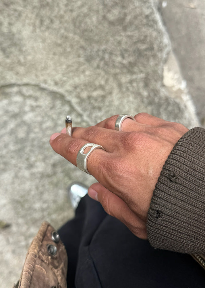 Man holding a cigarette, wearing silver rings
