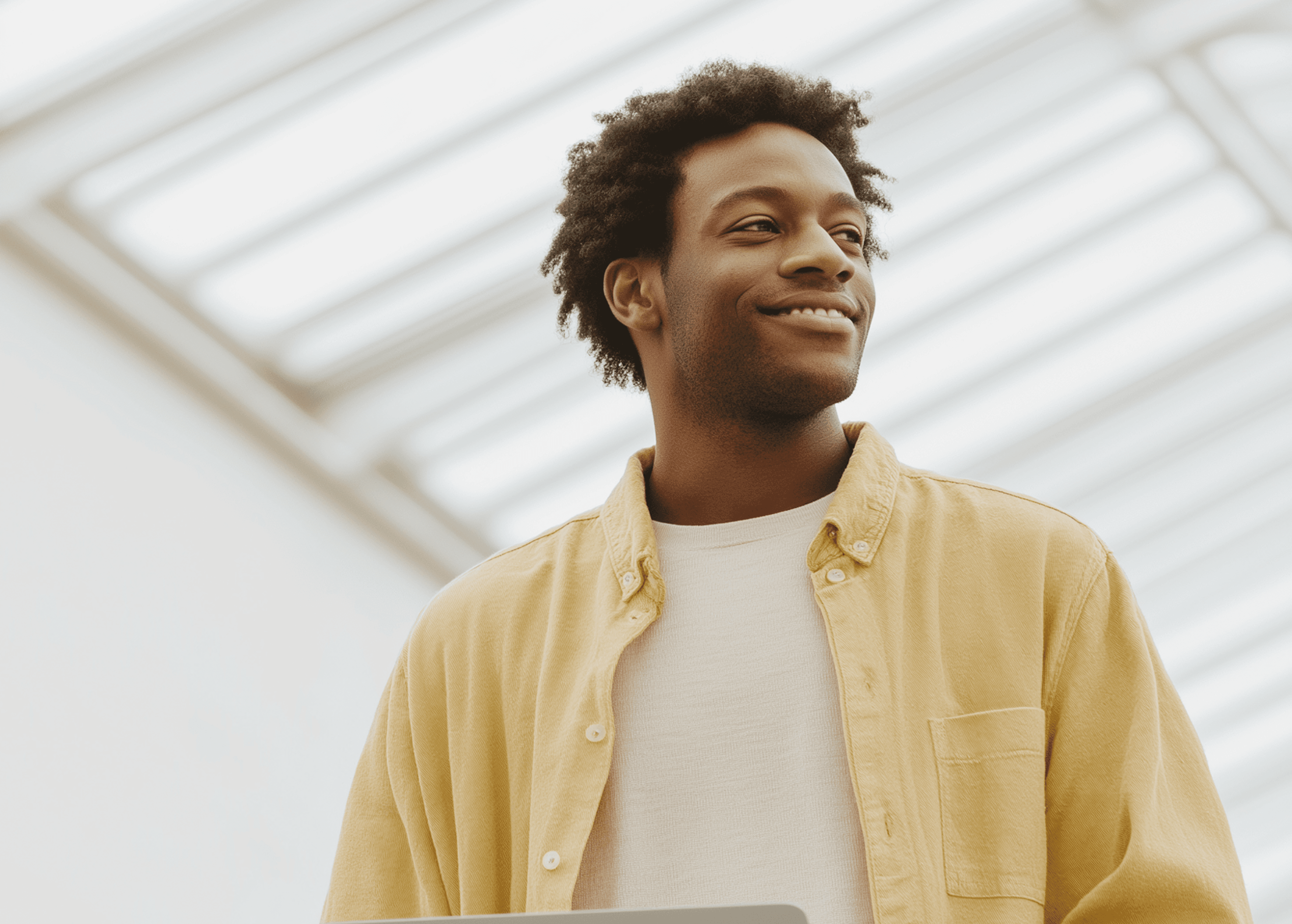 Smiling man in a yellow shirt looking away.