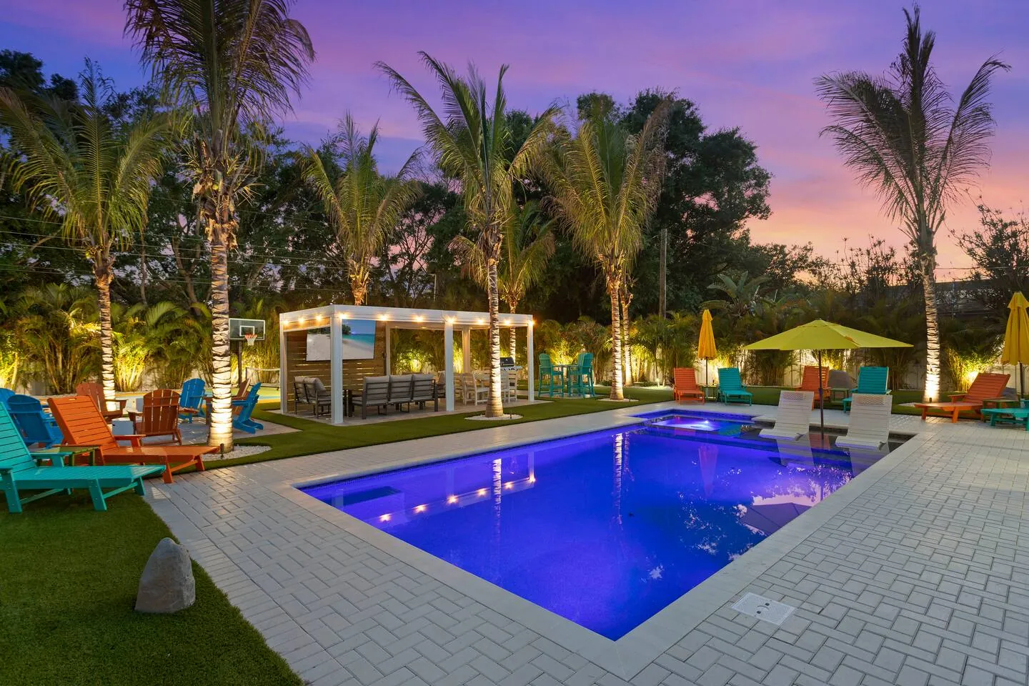 Pool lit at twilight with pergola and umbrellas at Private Backyard Resort, Bradenton, Florida