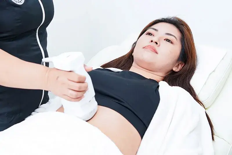 Client undergoing HIFU body treatment, a non-invasive skin tightening procedure that uses ultrasound energy to lift and contour the abdomen.