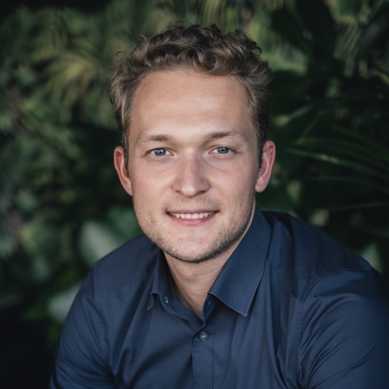 Smiling man wearing glasses and purple hoodie.