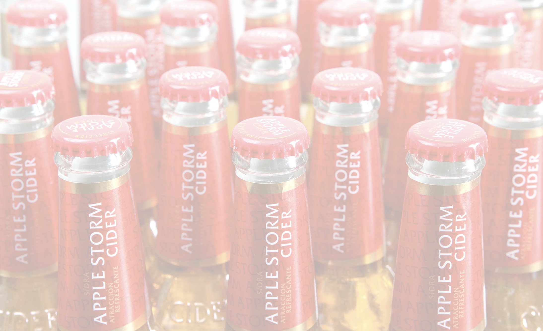 Filas de botellas de vidrio con tapas rojas etiquetadas como "Apple Storm Cider" crean un patrón juguetón y acogedor. El énfasis está en la marca de bebidas refrescantes.
