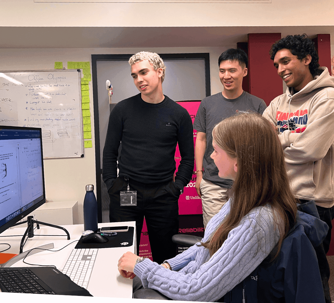 The interns gathered around a desk, looking at work on a screen