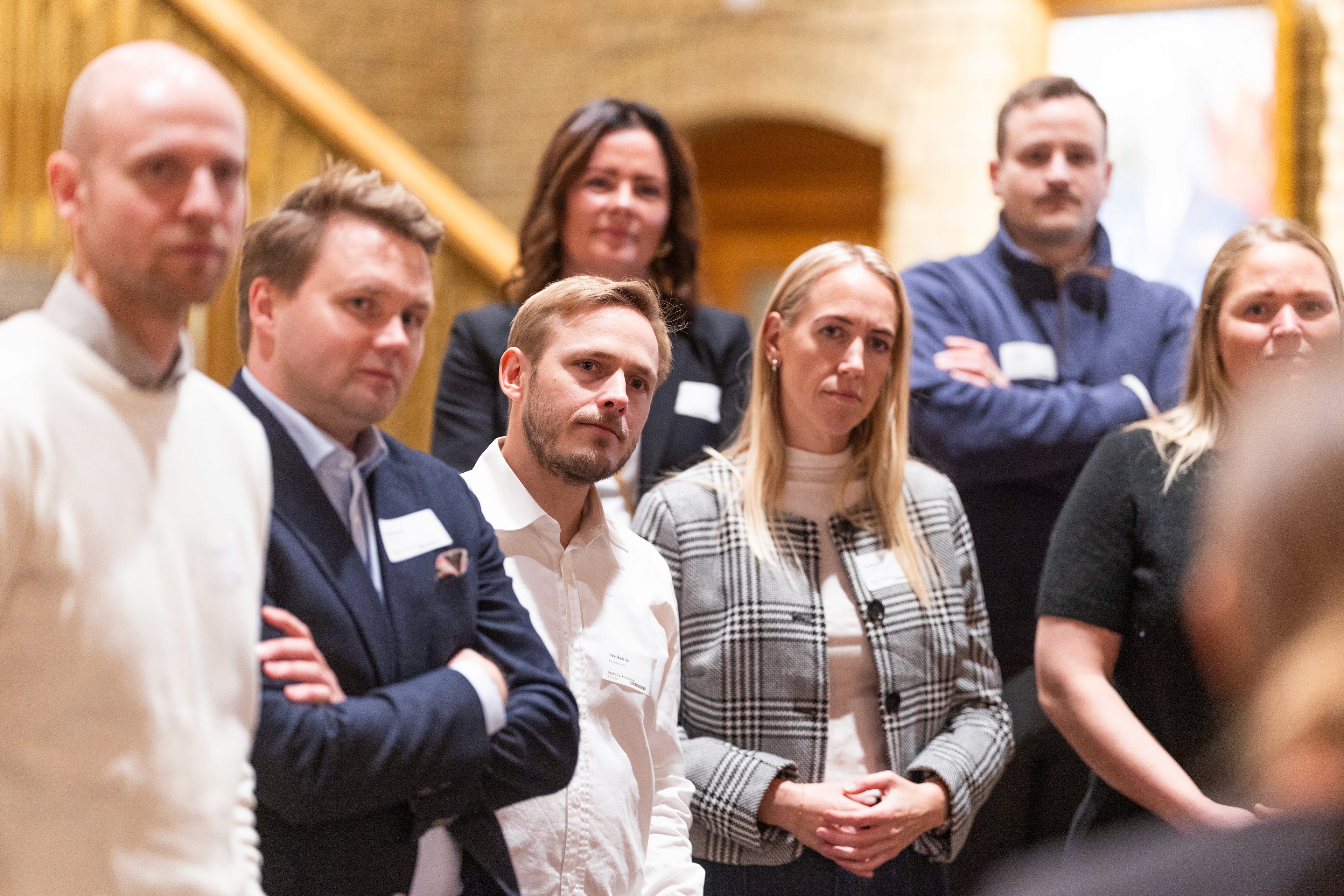 A group of people standing together, some with arms crossed, in a well-lit indoor setting.