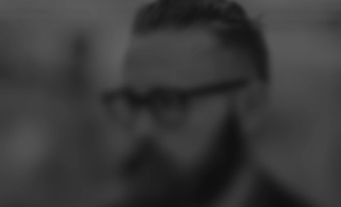Black and white blurred portrait of a bearded man wearing glasses