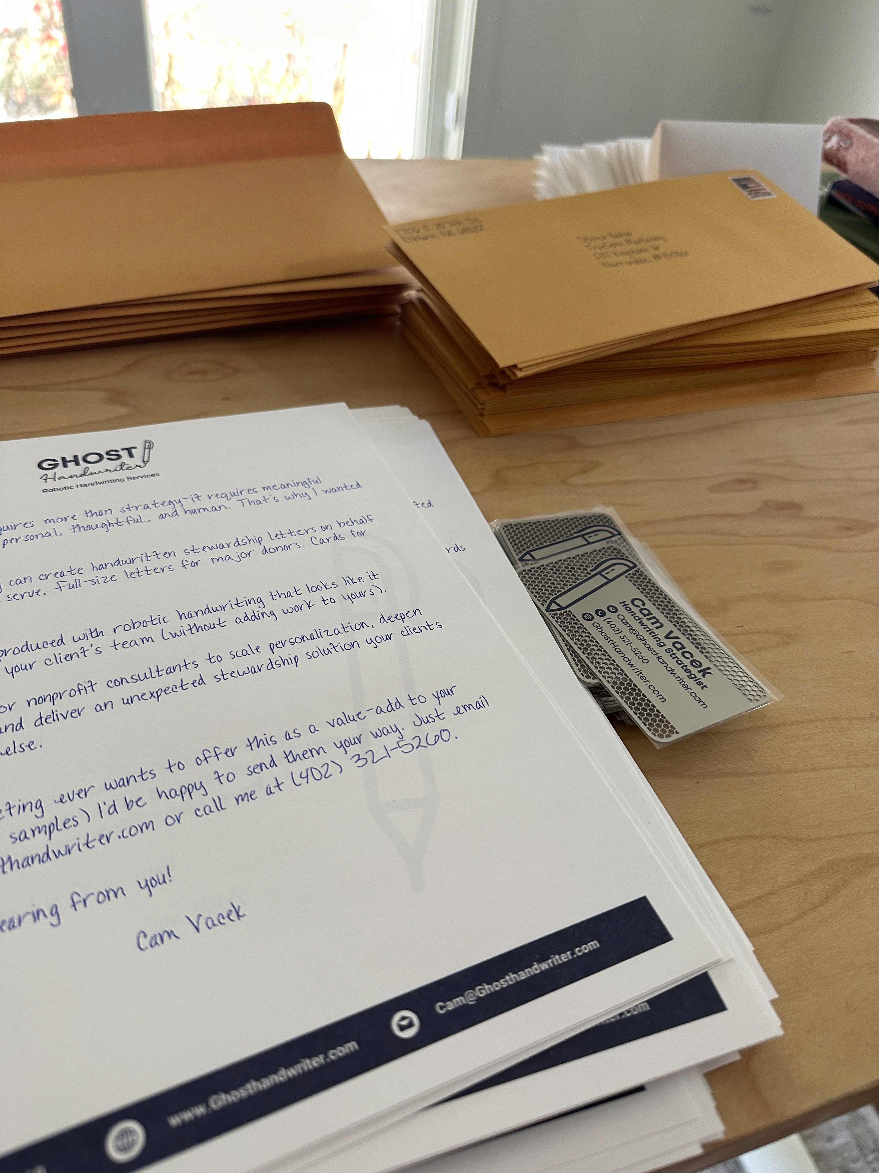 Handwritten letter beside stacks of addressed kraft envelopes