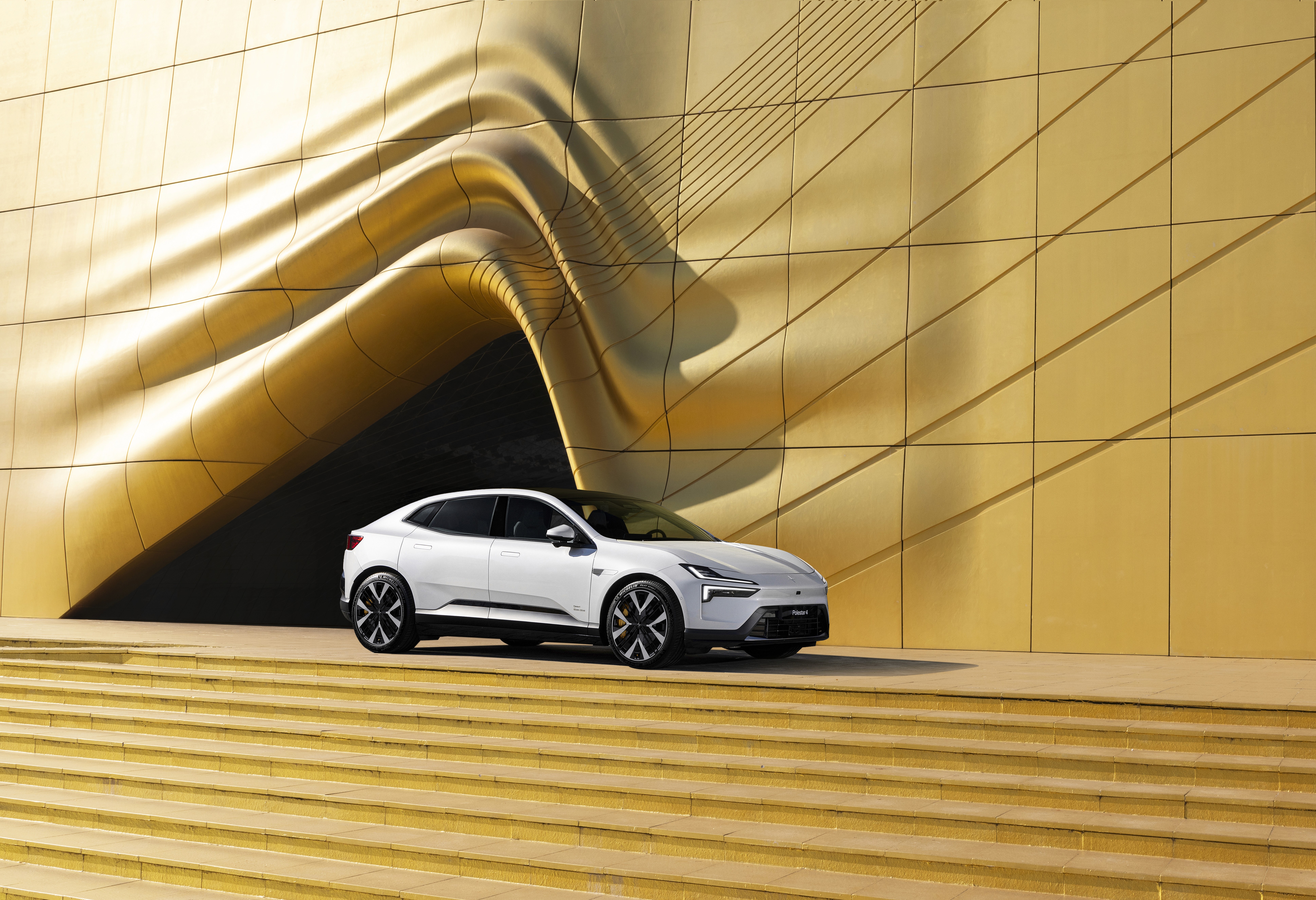 Polestar 4 blanche stationnée devant un bâtiment au design contemporain, SUV coupé électrique dans un cadre haut de gamme