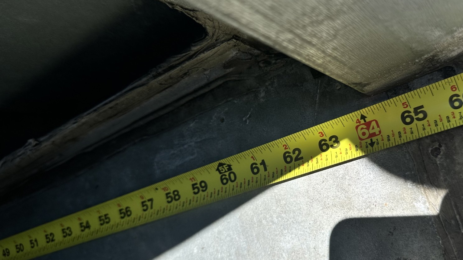 Close-up of a mechanical room doorway showing a tape measure across a narrow 64-inch opening — illustrating limited access space for HVAC fan replacements in New York City retrofit projects.