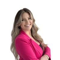 A smiling individual with long, wavy hair, wearing a bright pink blazer against a white background.
