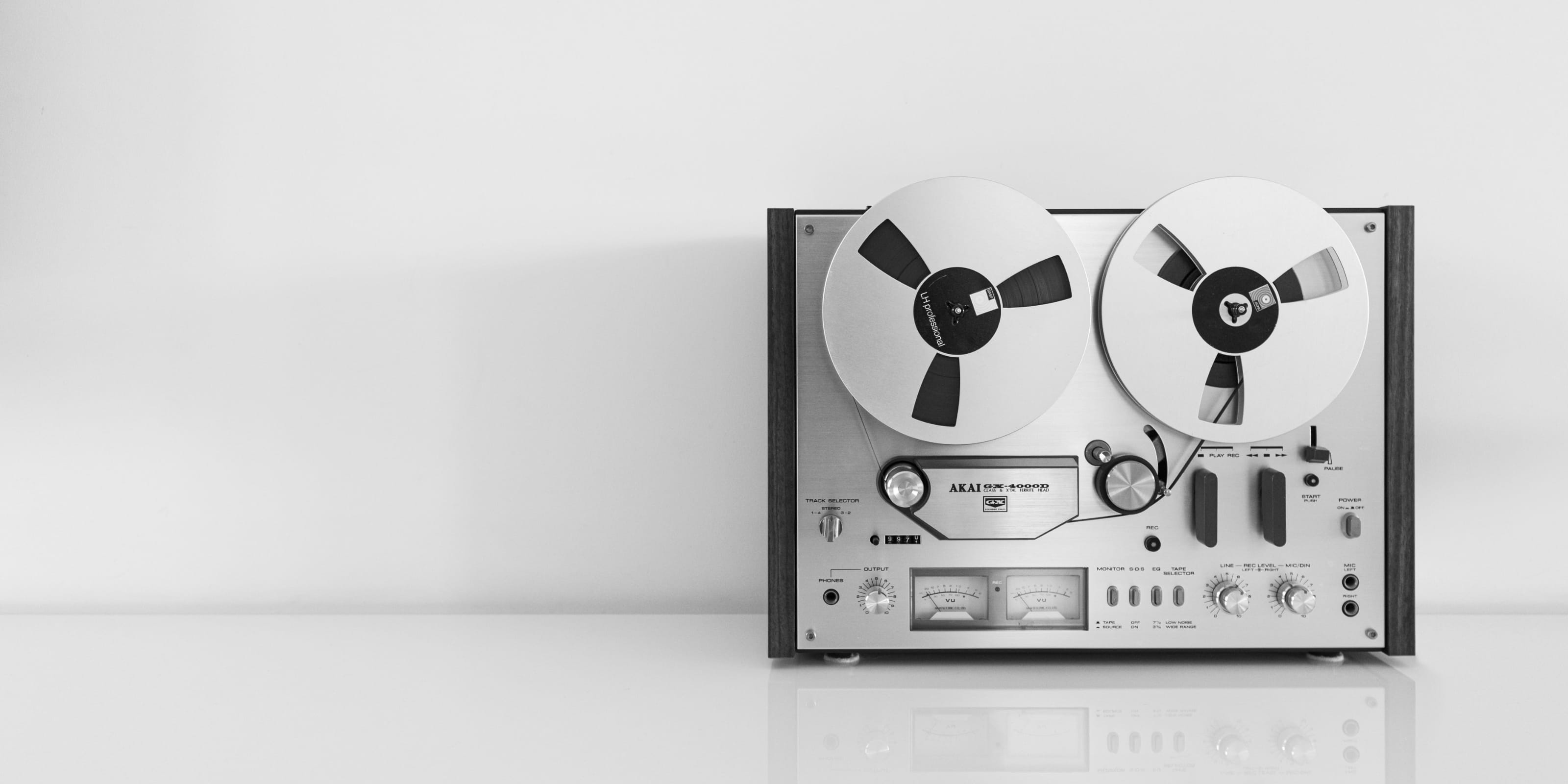 An Akai reel-to-reel tape recorder made of metal, wood, plastic, and glass.