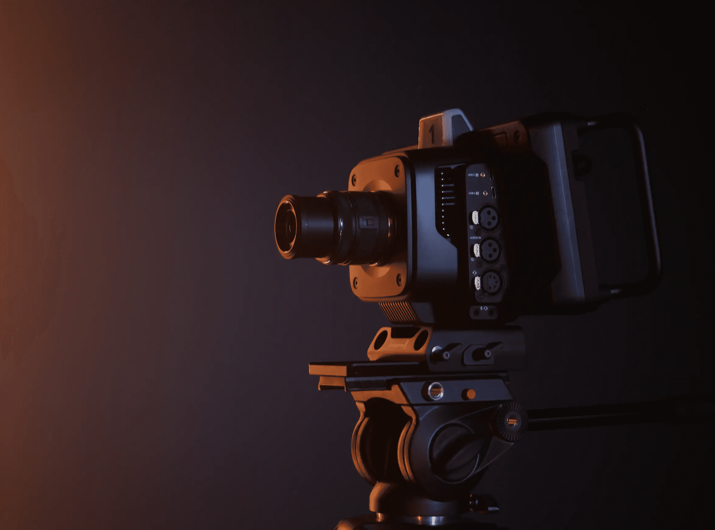 Caméra Blackmagic Studio Camera 4K Pro montée sur un trépied, éclairée par une lumière chaude sur fond sombre