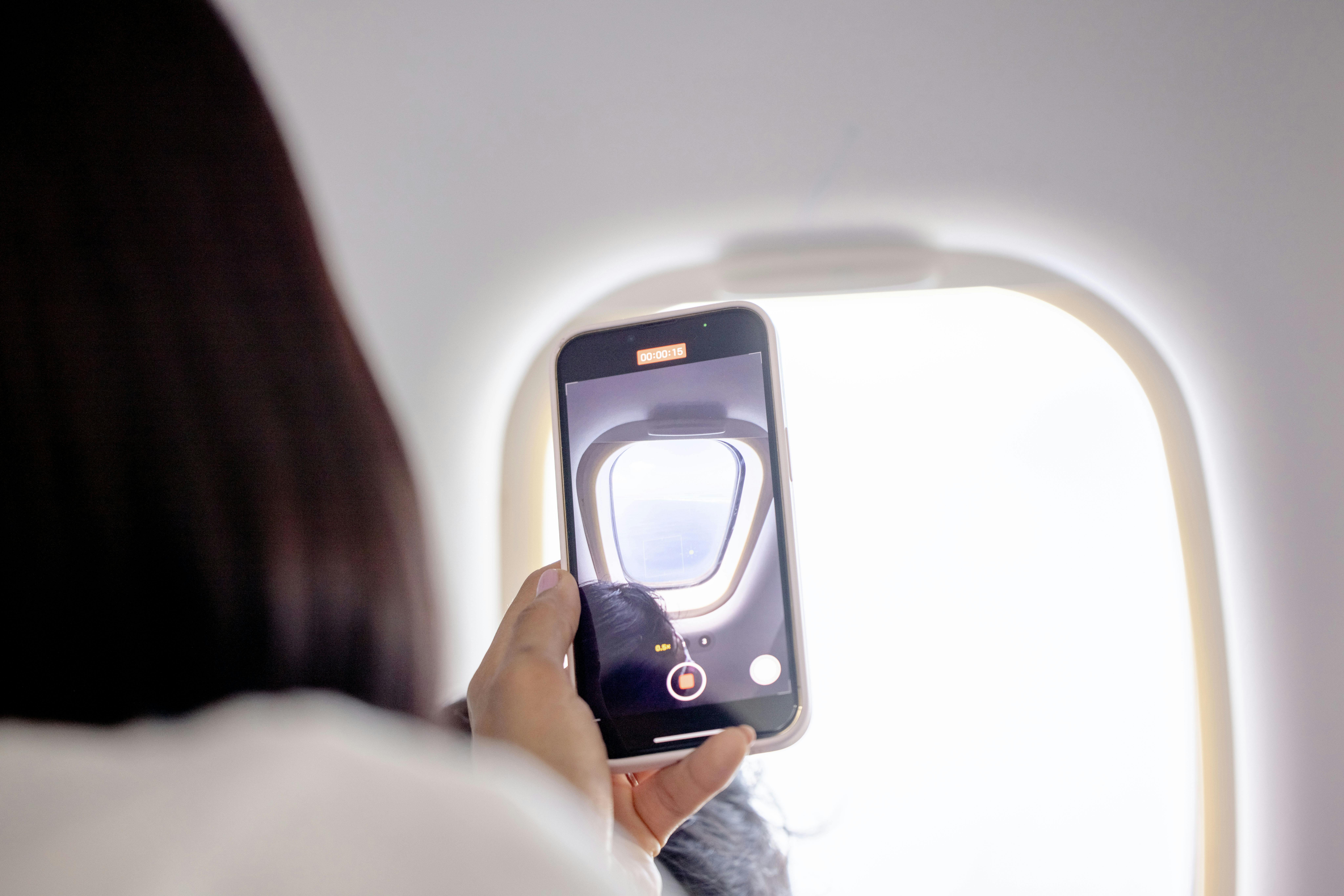 smartphone taking photo on plane outside window