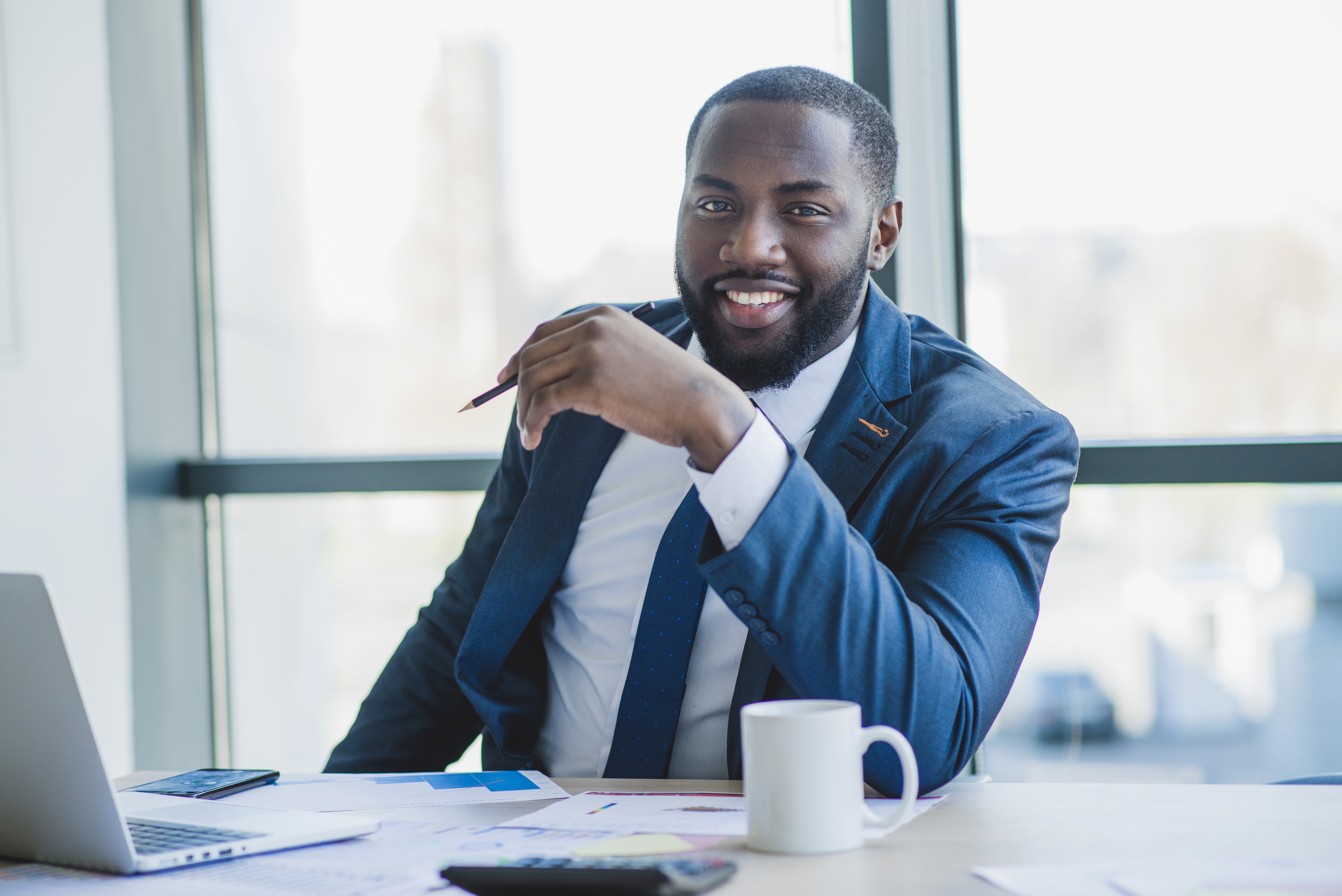 man in black suit jacket holding white ceramic mug