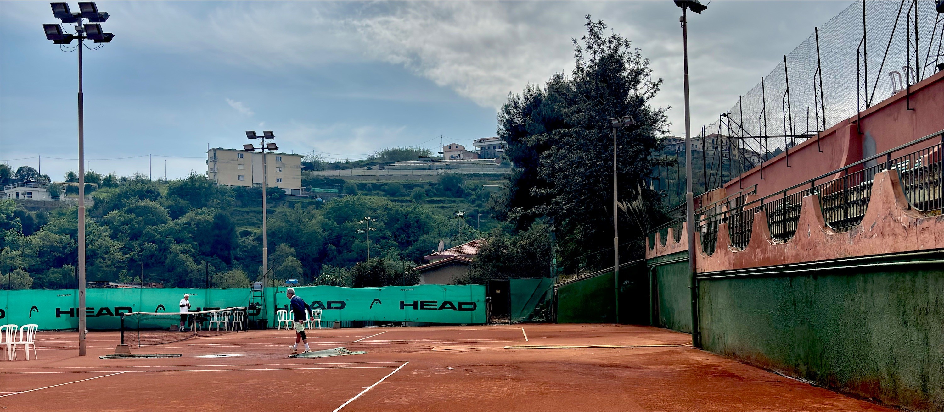 Red clay tennis courts under a broad sky in Sanremo