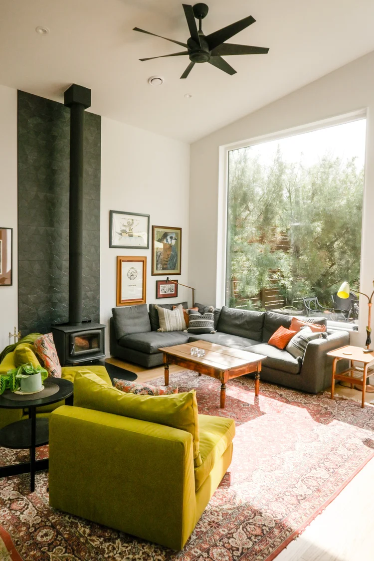 Modern two-story home with large glass windows, warmly lit interiors, and a balcony. Surrounded by trees and a manicured lawn at dusk. Cozy ambiance.