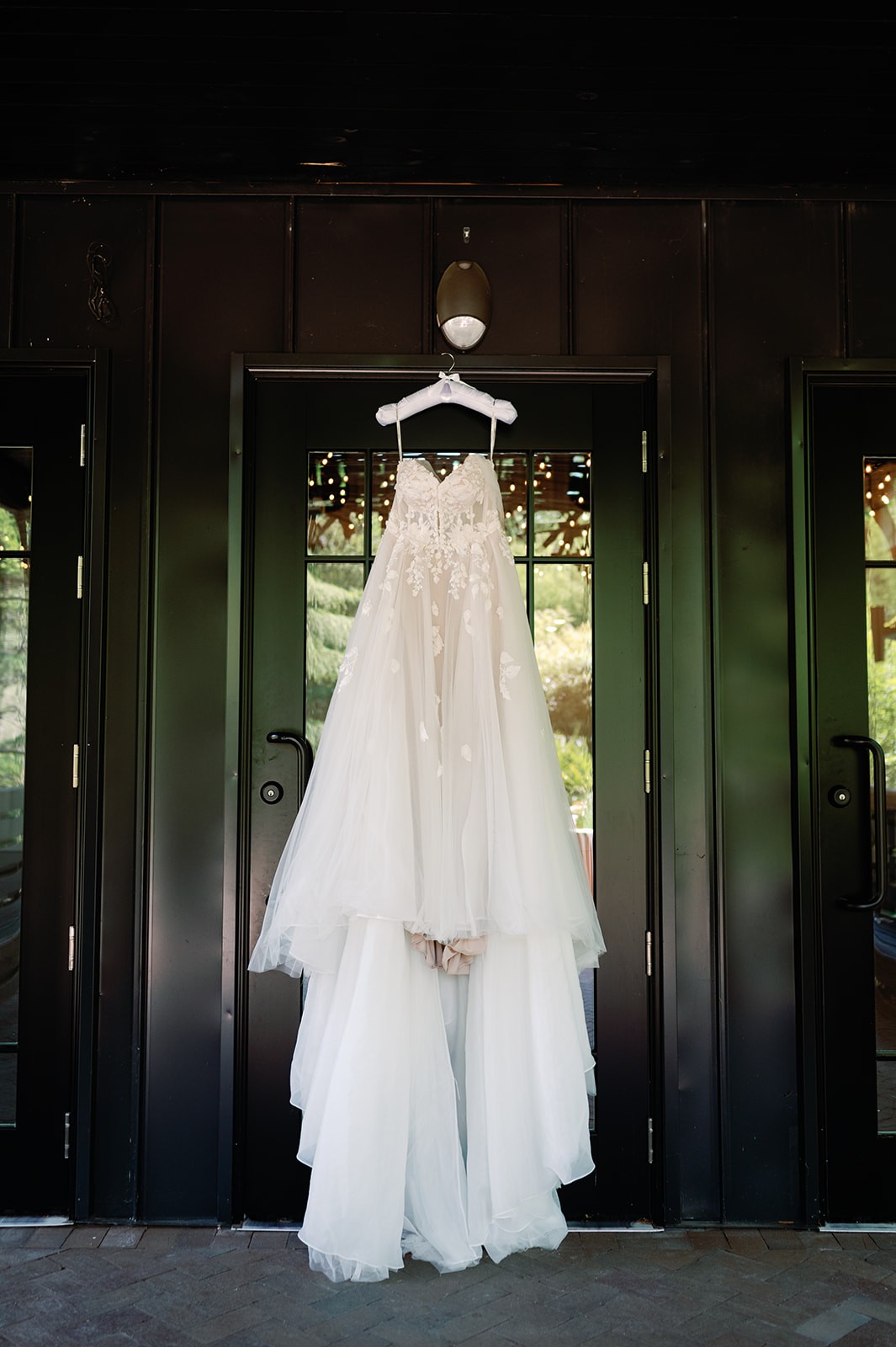 Lace wedding gown hanging in a glass doorway at Shiloh Gardens.